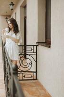 side view of young woman in bathrobe standing on hotel balcony enjoying view with cup of coffee, good morning, feeling positive, optimistic, new sunny day photo