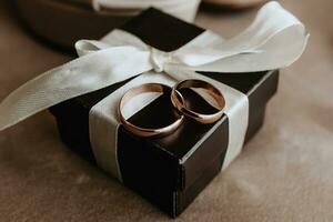 gold wedding rings on a brown box with a white ribbon photo