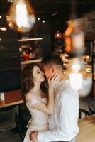 Side view portrait of a laughing European couple enjoying a date in a cafe with hanging retro lamps photo