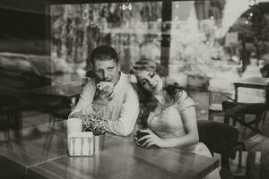 Side view portrait of a loving European couple laughing while enjoying a date in a cafe. Black and white photo