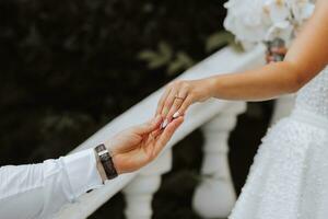 Hands of the bride and groom close-up. The groom holds the bride's hand photo