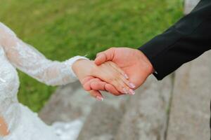 Hands of the bride and groom close-up. The groom holds the bride's hand photo