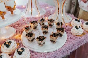 festivo postre mesa con dulces Boda caramelo bar, varios pasteles, chocolates en soportes foto