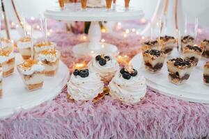 festivo postre mesa con dulces Boda caramelo bar, varios pasteles, chocolates en soportes foto