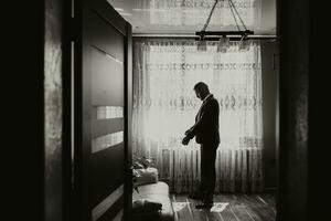 el novio es en su habitación por el ventana consiguiendo vestido y preparando para el Boda ceremonia foto