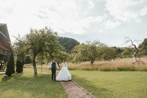 un hermosa boda, un hermosa Pareja en amar, caminando en el antecedentes de un verde jardín con alto verde arboles alto calidad foto