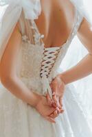 Photo of open beautiful shoulders of a bride wearing a wedding dress. Elegant hairstyle. Brown hair. Voluminous veil. Morning of the bride