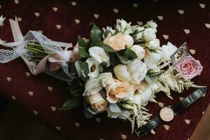 foto de Boda accesorios. lujoso ramo de flores de el novio. oro anillos en un estar con flores, un negro clásico reloj en un borgoña antecedentes.