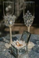 Wedding rings in a glass box, on a white flower. Wedding details. Holiday concept. The glasses are decorated with crystal flowers photo