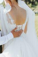 Wedding photo in nature. The bride's shoulders are open, the groom's hand is on the bride's shoulder. Beautiful hairstyle and hair decoration. Portrait of the bride and groom in the forest