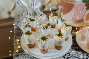 un delicioso boda. blanco pastel decorado con flores caramelo bar para un banquete. celebracion concepto. de moda postres mesa con dulces, dulces. frutas foto