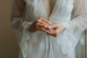 beautiful bride in a white robe with an open bust holding a diamond wedding ring The bride is preparing for the wedding. bride's fees the wedding day of the newlyweds. photo