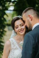 un Boda Pareja es disfrutando el mejor día de su vida en contra el antecedentes de verde hojas en el parque. retrato de novias en amor en naturaleza foto