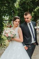 A wedding couple is enjoying the best day of their life against the background of green leaves in the park. Portrait of brides in love in nature photo