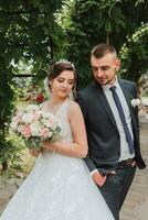 un Boda Pareja es disfrutando el mejor día de su vida en contra el antecedentes de verde hojas en el parque. retrato de novias en amor en naturaleza foto