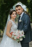 un Boda Pareja es disfrutando el mejor día de su vida en contra el antecedentes de verde hojas en el parque. retrato de novias en amor en naturaleza foto