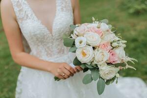 un Boda ramo de flores de blanco y rosado rosas en el manos de el novia. de cerca foto de el ramo de flores