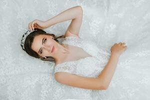 young beautiful bride with blue eyes in wedding dress, lying down, fashion shot under studio light. The photo is taken from above