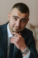 Confident elegant handsome guy at home sitting on the couch in a nice dark blue suit. photo