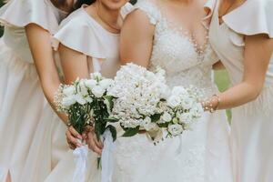 A group of beautiful girls with a bride in identical dresses are smiling, celebrating and having fun together against the background of nature and tall trees. Girls party photo