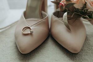 Beige open elegant shoes. A wedding ring with a diamond, a wedding ring made of roses. Fashion. Style. Wedding photo