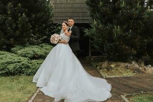 the bride and groom pose against the background of green trees. Wedding walk in nature in the park photo