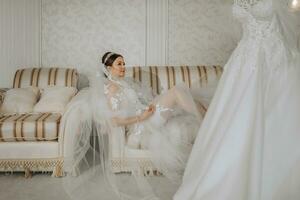 a beautiful girl with a wedding hairstyle and a tiara on her head in a transparent robe, lying on a bed in a hotel with a royal interior. Long veil, natural light, portrait photo