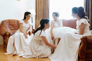 Wedding theme. A friend puts on the bride's shoes. Four brunettes. The last minutes of preparations for the wedding. The same outfit photo
