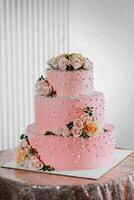 A delicious wedding. Pink three-tiered cake decorated with flowers. Candy bar for a banquet. Celebration concept. Fashionable desserts. Table with sweets, candies. Fruits photo