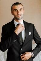 elegante hombre en un negro clásico traje con un atar. el novio es preparando para el Boda ceremonia foto