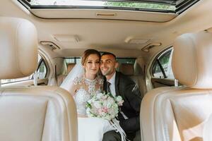 young happy bride and groom are rejoicing after the wedding ceremony in their car photo
