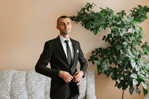 elegante hombre en un negro clásico traje con un atar. el novio es preparando para el Boda ceremonia foto