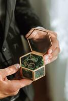 wedding rings lie in a beautiful glass box on green moss. Details of the verb during the morning meeting photo