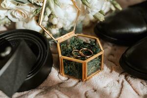 wedding rings lie in a beautiful glass box on green moss. Details of the verb during the morning meeting photo