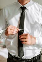 A man puts on a tie, a businessman prepares for a meeting. The groom is preparing for the ceremony photo