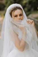 Happy stylish bride holding her veil and enjoying the best day of her life. Beautiful wedding dress, professional makeup and hair photo