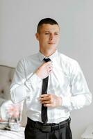 A man puts on a tie, a businessman prepares for a meeting. The groom is preparing for the ceremony photo