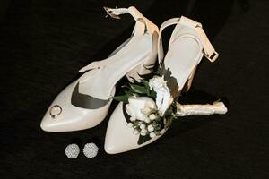 bride's wedding details, beige shoes, earrings, gold ring and rose boutonniere photo