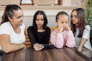 A child gets bored while adults or teenagers are busy or the concept of the effect of mobile phones on children's development, photo with selective soft focus