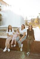 retrato de un grupo de joven muchachas y uno niño descansando y sonriente cerca un fuente foto