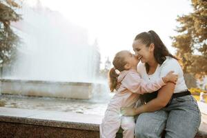 cerca arriba lado ver lleno de alegría sonriente joven madre y hija abrazando y reír, disfrutando oferta momento, contento mamá y adorable preescolar niña niño caricias, teniendo divertido juntos foto