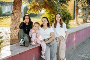 Portrait of a group of young girls and one child resting and smiling in the city photo