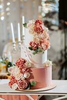 un delicioso boda. rosado tres niveles pastel decorado con flores caramelo bar para un banquete. celebracion concepto. de moda postres mesa con dulces, dulces. frutas foto