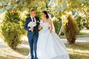 Happy bride and groom after wedding ceremony. Long veil. Chic white dress with open shoulders. A bouquet of orchids. During sunset photo