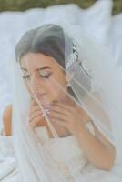 tender portrait of a happy bride with a bouquet of orchids in her hands, outdoors. Warm summer time. A long veil, a luxurious white dress with a train. photo