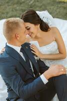 contento novia y novio después Boda ceremonia. largo velo. elegante blanco vestir con abierto espalda. un ramo de flores de orquídeas. durante puesta de sol foto