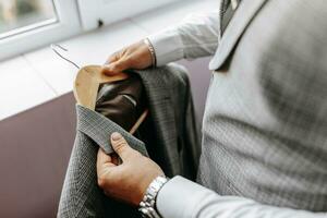 close-up of man's hands holding his jacket. The groom is preparing for the wedding. The man is wearing a white shirt and a suit. Stylish groom photo