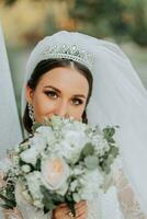 Portrait of the bride with a bouquet. A beautiful young bride holds a wedding bouquet in her hands. Wedding hair and makeup photo