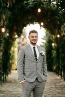 Handsome bearded man, groom in gray suit and black tie standing outdoors. Wedding portrait. A man in a classic suit photo