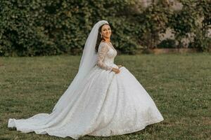 Portrait of the bride in a white dress and a crown on her head is walking in the park. Professional wedding makeup and hair. Beautiful young bride. Happy woman. photo